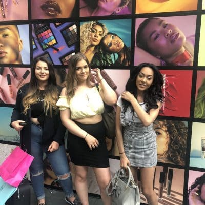 Hair & Media Make-Up students in front of makeup graphic wall