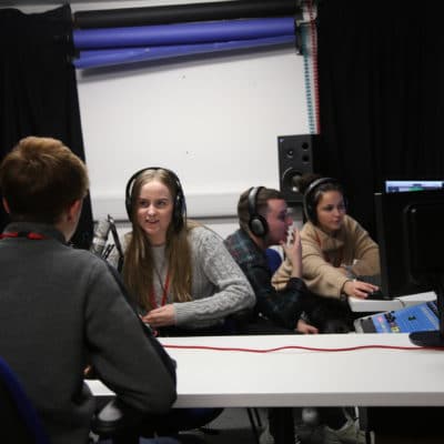 students in studio one pair interviewing each other and other working on computers