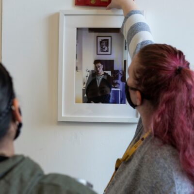 two female students make sure a picture is level on the wall