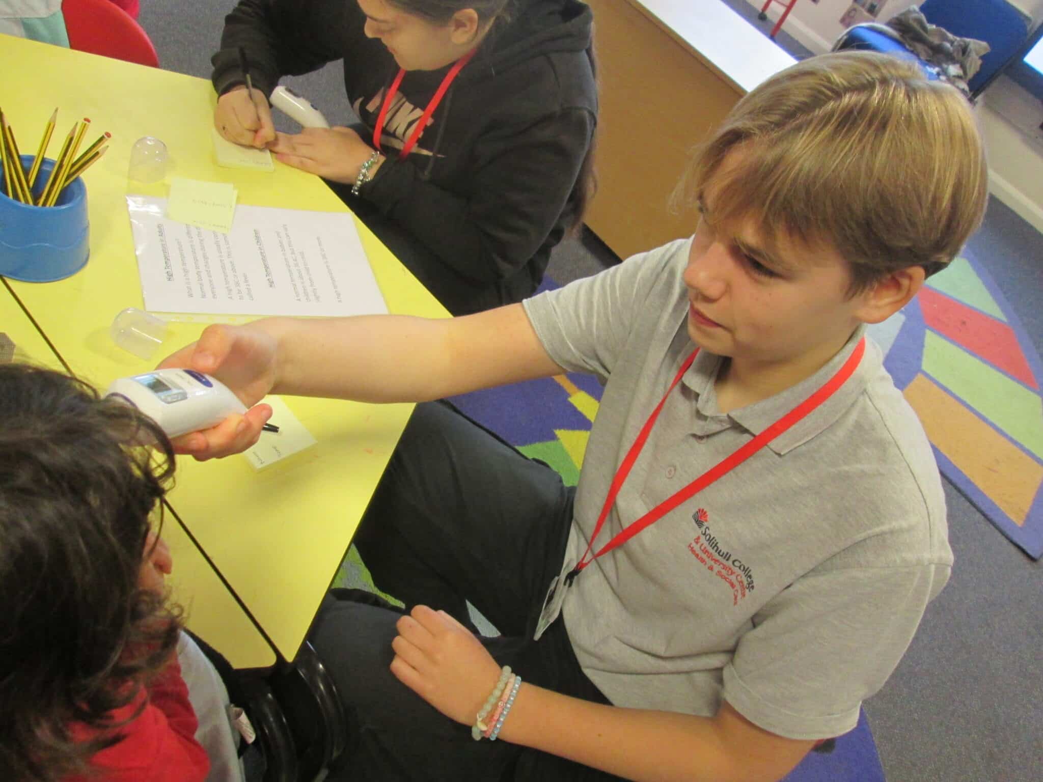 student taking the temperature of a school pupil