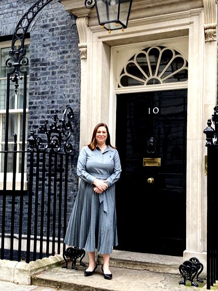 Principal standing in front of the door of 10 downing street wearing a blue dress