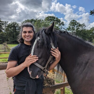 student stood next to horse with hands around its head