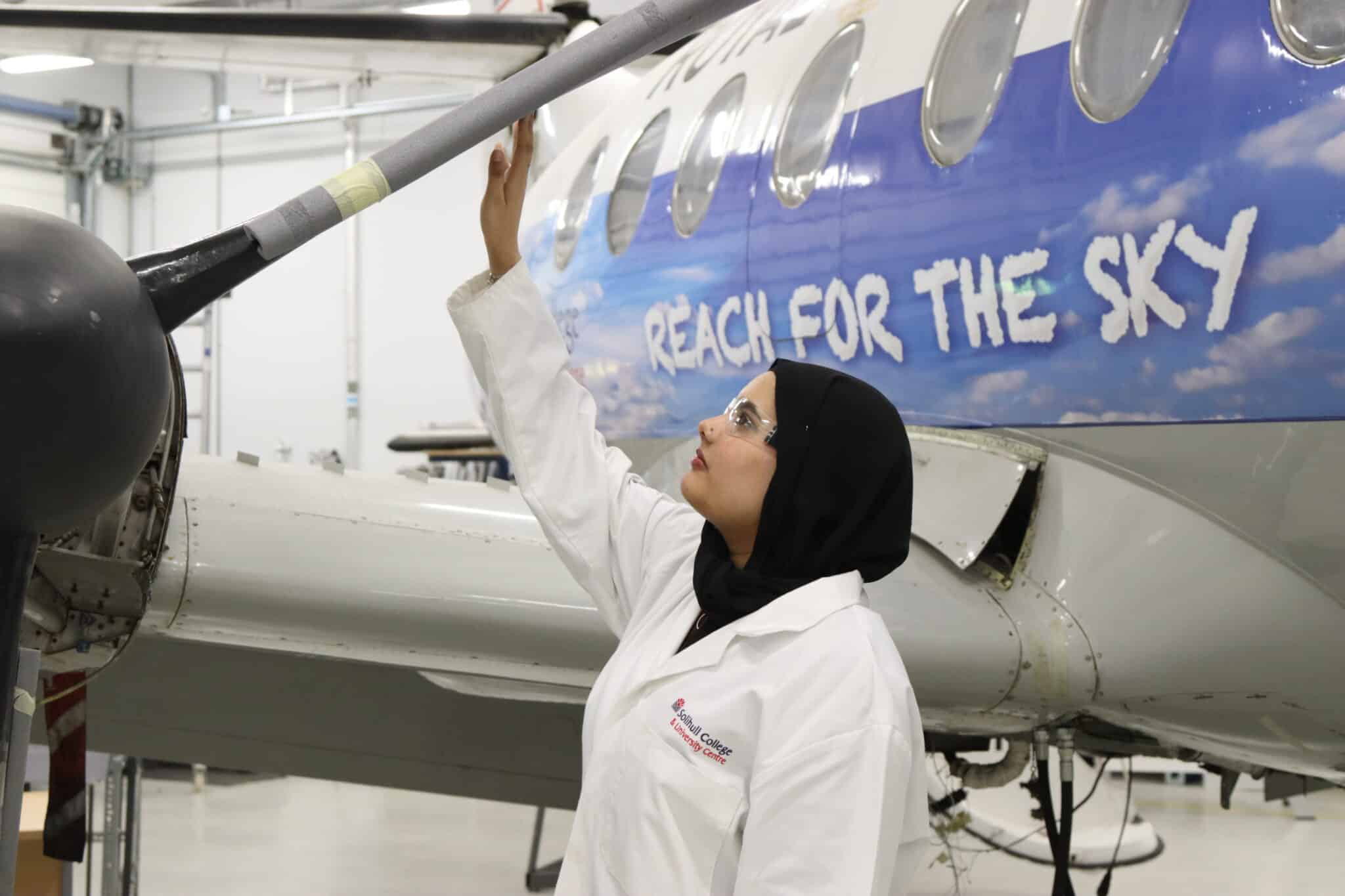 Nimrah touching the wing of college aircraft