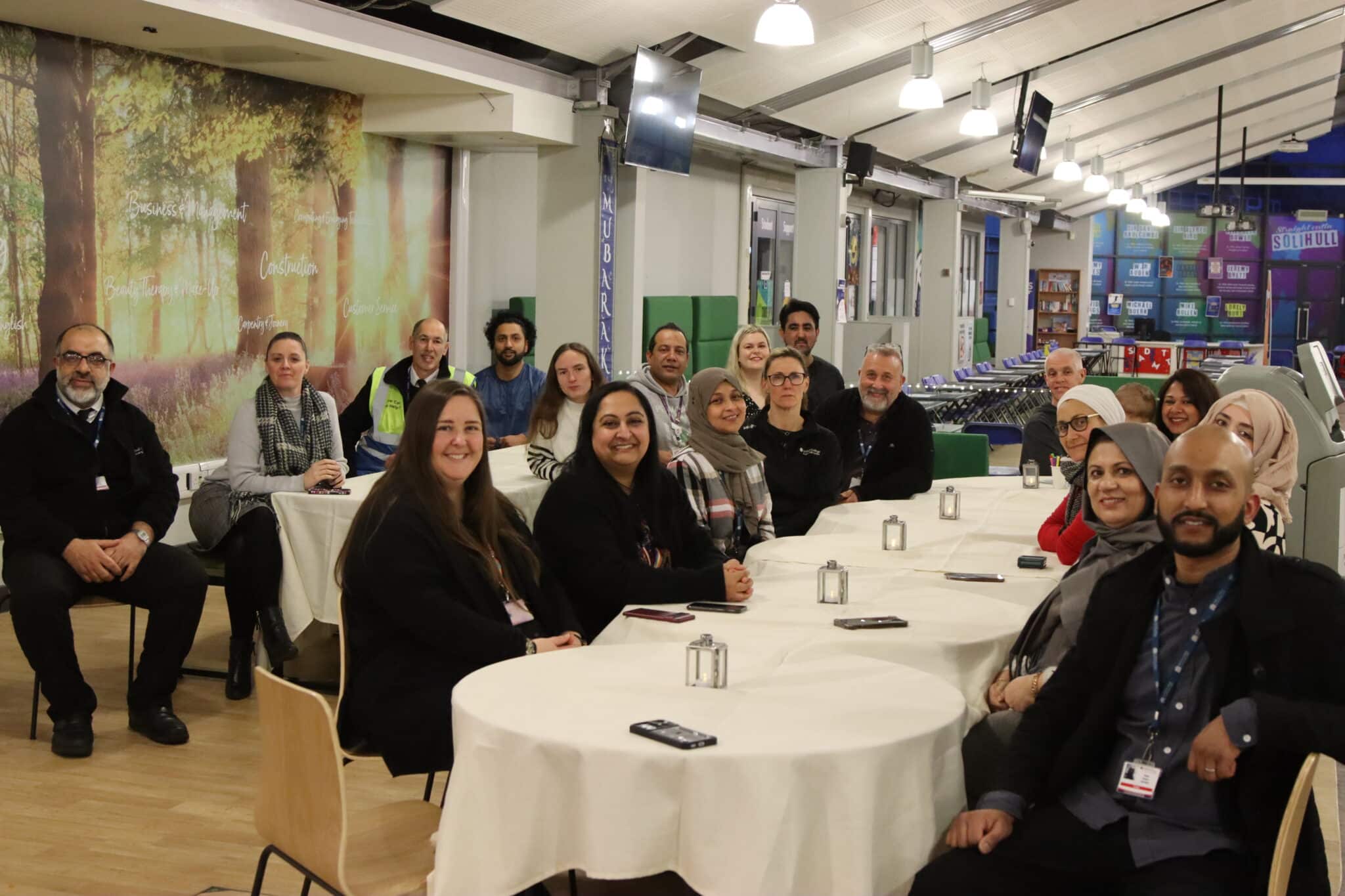 A photo of staff sat around tables looking at camera