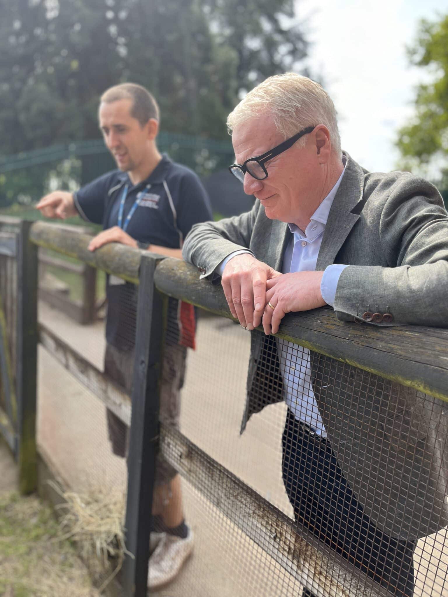 Mayor of the west midlands leaning over a fence in the animal department