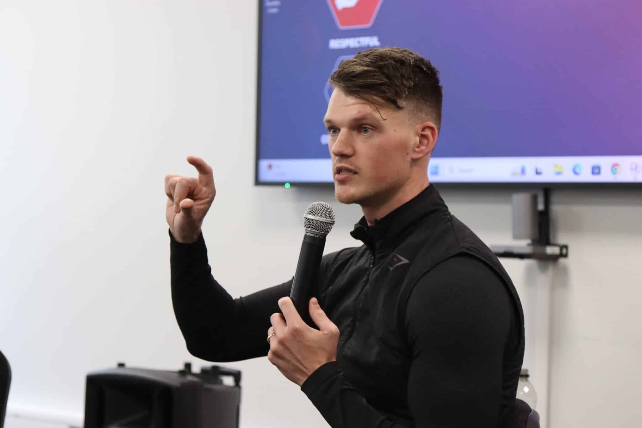Ben Francis from Gymshark talking with a mic to students