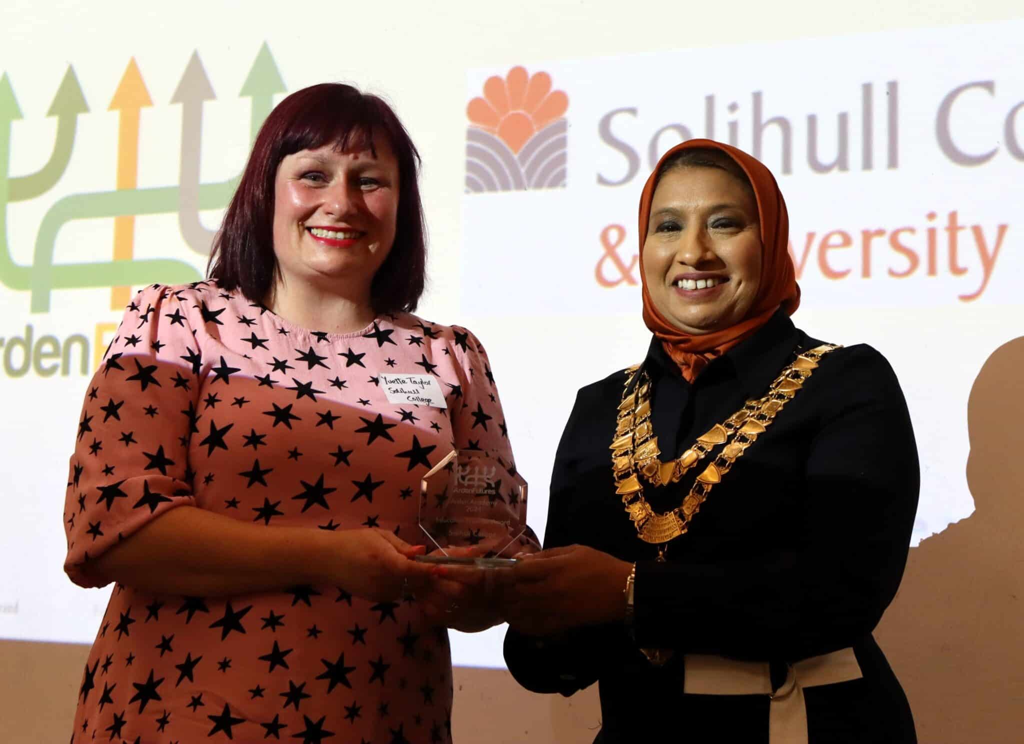 Yvette and the Mayor of Solihull stand in front of powerpoint with award