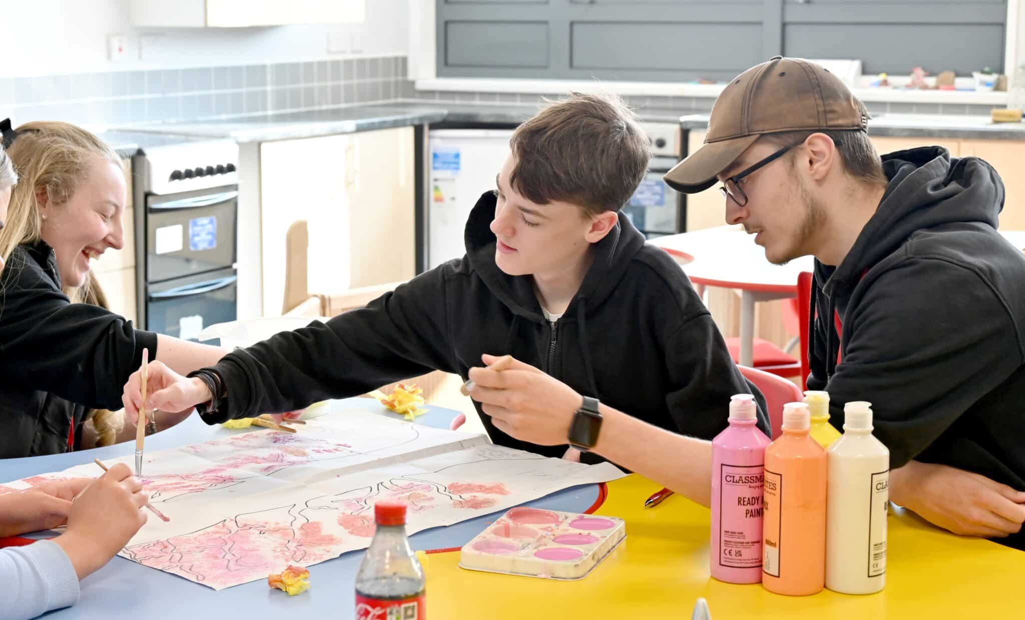 students working at a desk with colourful pictures working in childcare