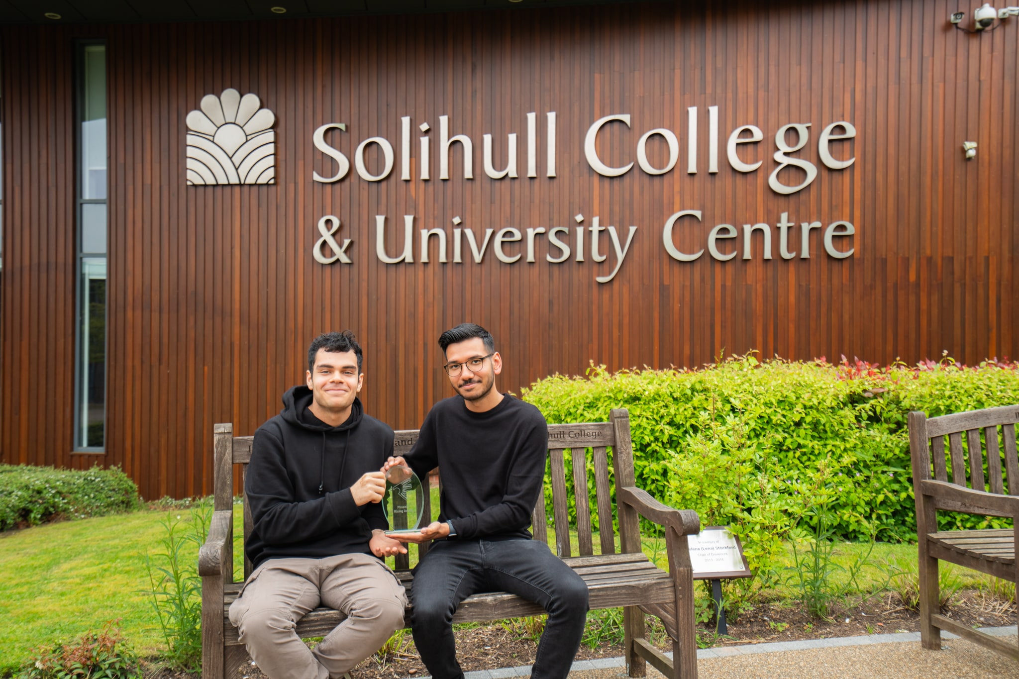 sam and juan sat on bench in front of solihull college & university centre logo