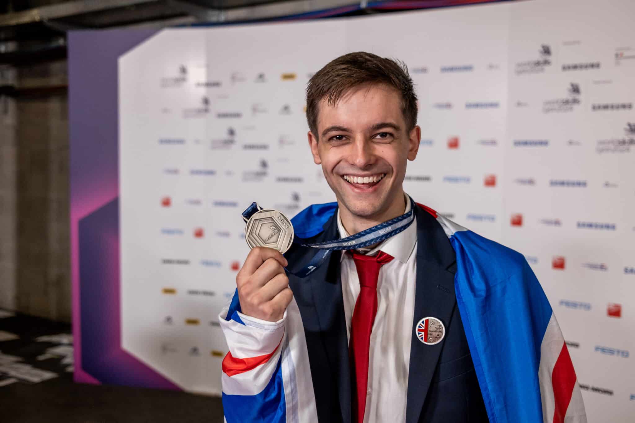 Harry holding up his silver medal with big smile on face