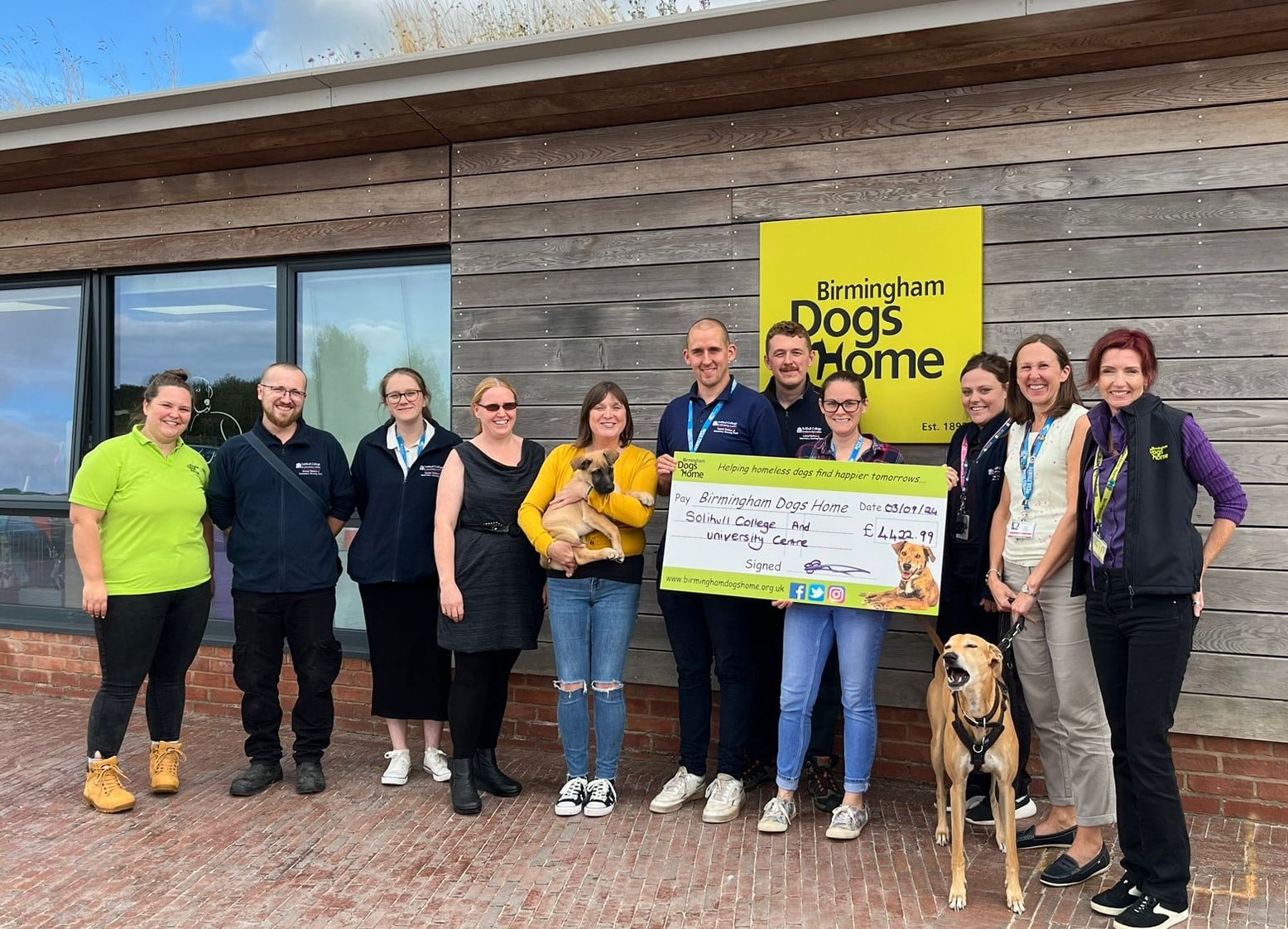 staff from solihull college & University centre handing over a large cheque to the staff at birmingham dogs home