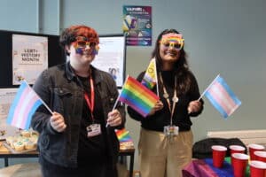 staff and student standing with pride flags